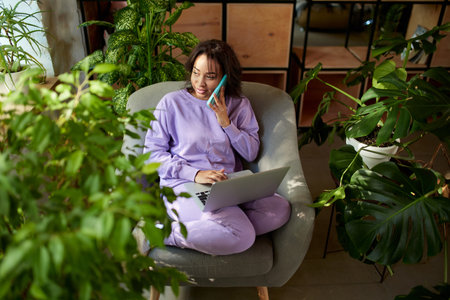 Portrait of woman sitting on chair and making online order on phone. Home interior background. Concept of shopping, online order and delivery, Black Friday sales. Copy space for ad, textの写真素材