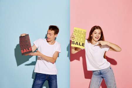 Portrait of young people, man and woman in casual clothes holding paper with big sales information....