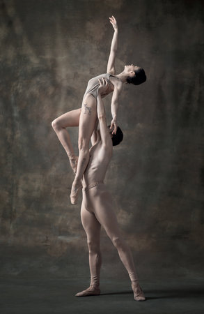 Young man and woman, ballet dancers performing isolated over dark green vintage background. Holding high. Grace. Contemporary ballet. Concept of classic dance, artist, beauty. Copy space for adの写真素材