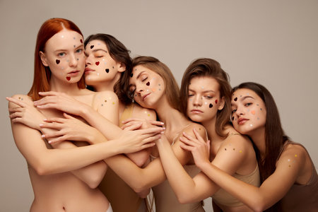 Portrait of young beautiful women posing in beige underwear isolated over grey background. Tenderness and sensuality. Concept of beauty, freedom, emotions, extraordinary fashion, modern style, youthの写真素材