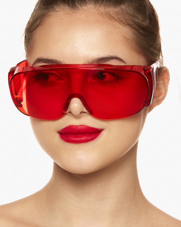 Portrait of young beautiful girl posing in red plastic glasses isolated over white background. Laser...