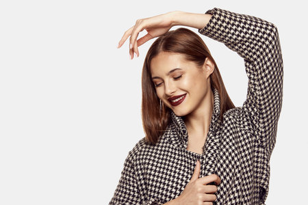 Portrait of young beautiful girl posing in stylish jacket isolated over white background. Deep red...