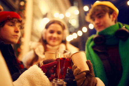 Emotional young people, friends meeting, smiling, drinking hot drinks at evening city street at winter time. Emotions, love, friendships, ad, sales concept. Winter fashion collectionの写真素材