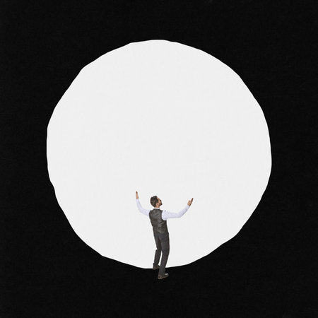 Young man standing in front of giant white circle. Minimalism. Ideas, inspiration, motiovation. Concept of business, personal and professional growth, personality psychology achievement adの写真素材