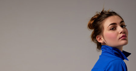 Fashionable stylish emotional woman wearing blue shirt posing over gray background. Model with vivid facial expression. Concept of fashion, style, youth, beauty. Closeupの写真素材