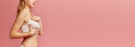 Cropped image of female body. Girl checking lumps on her breast for signs of breast cancer over pink background. Women healthcare, mammography concept. Banner for ad, textの写真素材