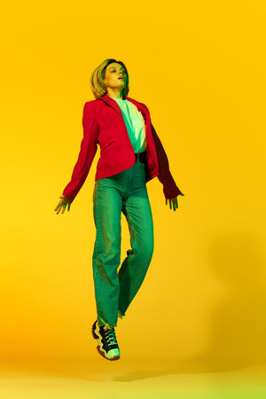 Freedom, happiness. Young girl in casual clothes moves above ground, levitating over yellow background. Concept of calmness, mind health, youth, emotions, fashion. Copy space for adの写真素材