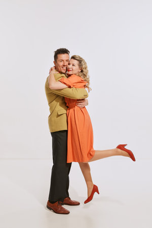 Long-waiting. Young happy man and woman, family couple in retro style clothes hugging isolated over light background. Concept of love, relationship, retro style, creativity, family. Copy space for adの写真素材