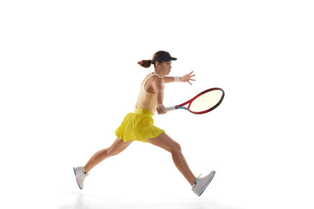 Dynamic portrait of young teen girl, tennis player in sports uniform in action isolated over white...