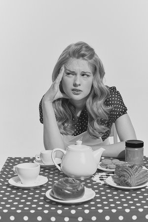 Retro blond. Monochrome portrait of young beautifl girl sitting at the table. Thoughtful look....