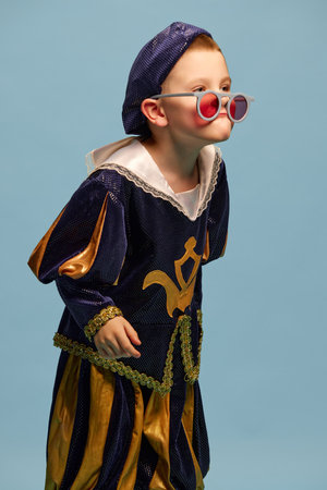 Portrait of little charming boy in costume of medieval pageboy, little prince having fun over light...