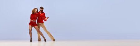 Young flexible couple of dancers in bright retro fashion clothes, stage costumes dancing over light background. Concept of music, art, dance, retro. Banner with copy space for adの写真素材