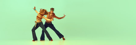 Incendiary dance. Emotional man and woman in retro style clothes dancing disco dance over green...