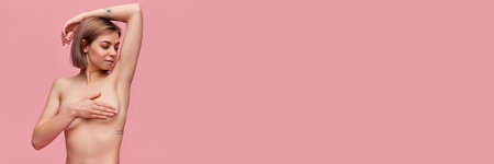 Young woman examining her breast over pink background. Concept of female health, annual medical...
