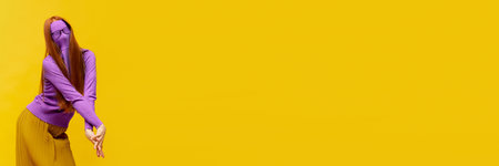 Weird people concept. Faceless portrait of slim woman with long straight red hair wearing retro fashion outfit in action over yellow studio background. Impersonal emotions, body language. Bannerの写真素材