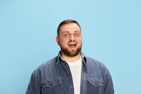 Surprise. Bearded handsome bearded man wearing jeans jacket smiling with surprised face and looking...