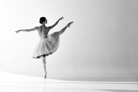 Monochrome. Elegant movements of one beautiful ballerina dancing with pleasure. Female dancer in ballet dress. Concept of art, beauty, aspiration, creativityの写真素材