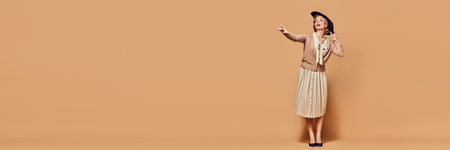 Banner of charming woman wearing black hat pointing with hand to side and looking away over beige background. Concept human emotions, fashion, beauty, retro style, vintage, 60sの写真素材