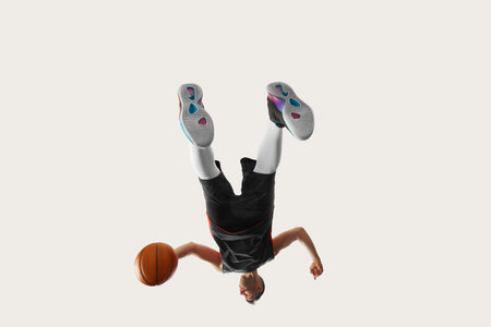 Non-standard shot. Unusual angle of streetball player wearing sport clothes and training over white background. Concept of sport, health, active lifestyleの写真素材