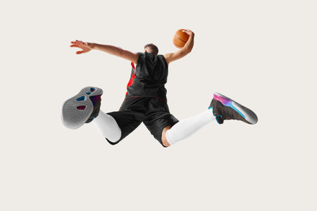 Goal. Portrait of male professional basketball player jumping and throwing ball into the basket over white background. Bottom view. Concept of sport, health, active lifestyle, competitionsの写真素材