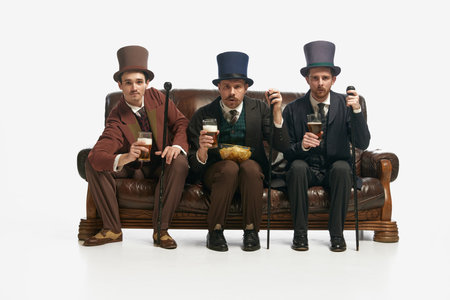 Fun evening meeting. Portrait with three men wearing old-fashioned clothes sitting on sofa with...