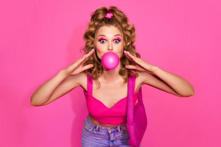 Girl with bubblegum. Portrait of beautiful girl woman wearing stylish clothes, jeans and top posing over pink studio background. Concept of fashion, beauty, vintage, youth, life style, adの写真素材