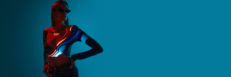Banner with one stylish woman wearing black sunglasses with digital neon filter lights on clothes over blue background. Copy space for ad, text. Concept of art, fashion, cyberpunk, modern, creativity.の写真素材