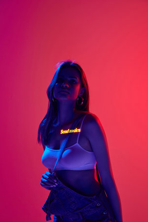 Virtual reality, game. Attractive woman with sad eyes and digital neon filter lights on body on red...