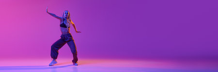 Portrait with young adorable girl dancing unusual movement over gradient purple background in neon...