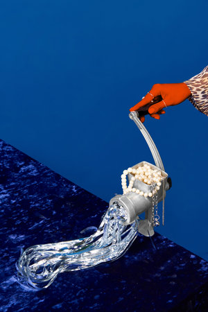 Strange things. Portrait of female hands using meat grinder for cooking jewelry over dark blue studio background. Concept of weirdness, meal, beauty, fashion, food, cuisine, creative, adの写真素材
