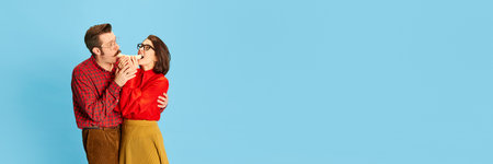 Banner with couple handsome man and beautiful woman sharing, eating banana for two over blue...