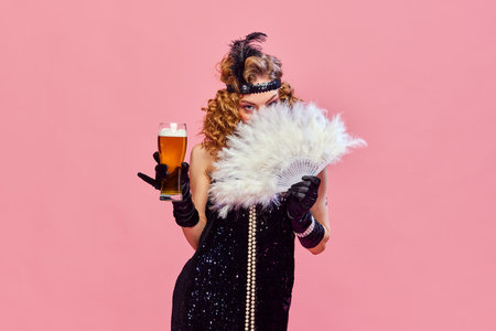 Mysterious woman wearing black vintage dress covers her face with hand fan and holding foamy beer...