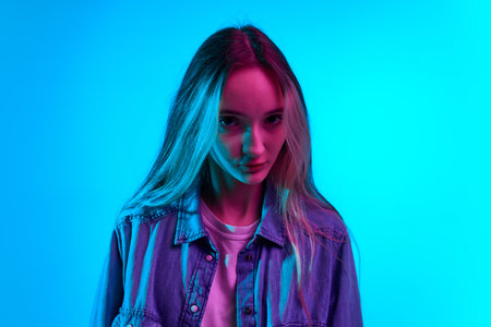 Piercing gaze. Close up portrait of young charming girls face with big beautiful eyes over blue...