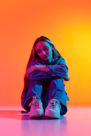Unrequited love. Portrait with one charming sad, upset girl with long hair sitting at floor alone...