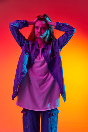 Spoiled mood. Back view portrait with sad, upset teenager, girl with long hair posing over red background in neon light. Concept of beauty, youth, human emotions, fashion, temporary difficulties, adの写真素材