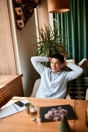 Successful businessman in suit managing his business, project remotely sitting in cafe leaning on...