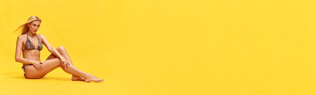 Beautiful young woman with perfect, slim, tanned body in stylish swimsuit over yellow studio background. Concept of summertime, fashion, female beauty, vacation, lifestyle. Banner. Copy space for adの写真素材