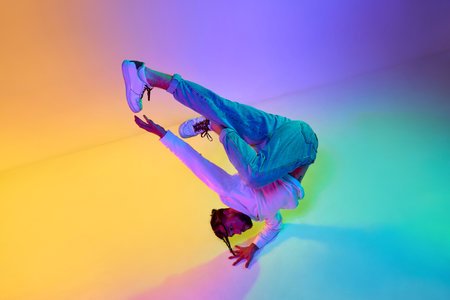 Creative young guy in casual clothes dancing hip-hop contemporary, breakdance against gradient...