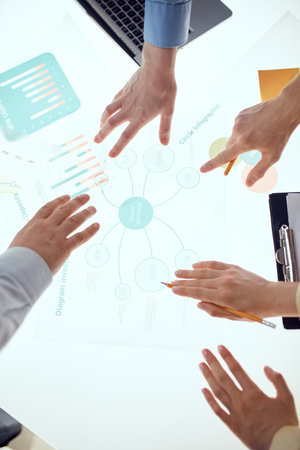 Brainstorming. Human hands during the conference in office over illuminated desk with graphs,...