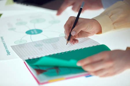 Female hands making notes at notebook during brainstorming, business meeting. Concept of work, exam,...