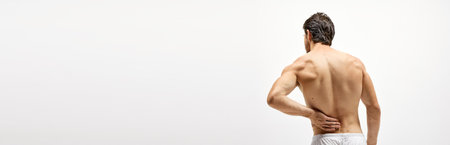 Horizontal banner with half-length portrait of shirtless man standing his back to camera. Man experiencing back pain. Concept of health, medicine, ad. Copyspace for adsの写真素材