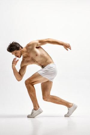 Masculinity and strength. Young handsome Caucasian man wearing homewear posing over white studio background. Concept of mens health, beauty of male body, fashion, adの写真素材