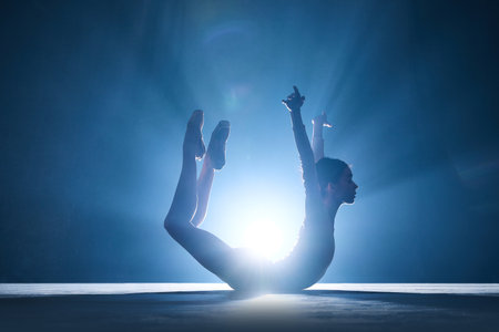 Expressive, artistic young woman, professional ballerina making creative performance against dark blue background with spotlight. Concept of art, classical ballet, creativity, choreography, beauty, adの写真素材