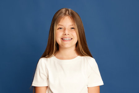 Laughing. Half-length portrait of charming little girl looking at camera over blue background. Kids...
