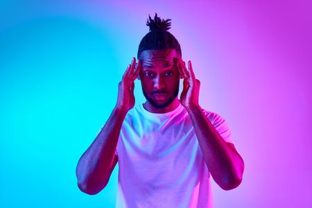 One african man focused on something and holding his hand looking away over colorful studio...