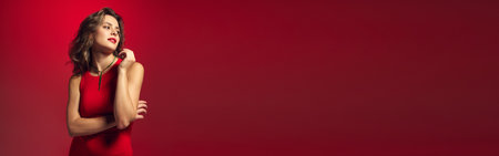 Dreaming woman, young fashion model wearing fashionable tight red midi dress posing over gradient burgundy neon background. Banner for ad. Concept of beauty, fashion week, sales, human emotions, trendの写真素材