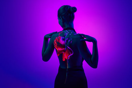 Portrait with sensual female silhouette in digital neon filter lights with red flower on back over...