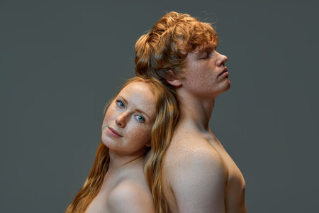 Fashionable loving redhead couple. Handsome man and beautiful woman with bare shoulders standing back to back in the studio. Concept of natural beauty, love, relationships, fashion. Ad.の写真素材