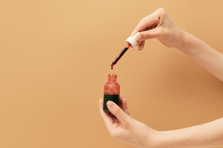 Close up image of female hand with jar of serum, liquid peeling in pipette holding in hands isolated beige background. Anti-aging. Concept of body and skin care, spa, dermatology. Copy space for adの写真素材