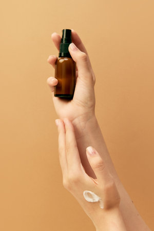 Vertical cropped photo of female hand holding jar of cosmetic product and swatch of cream for hands...